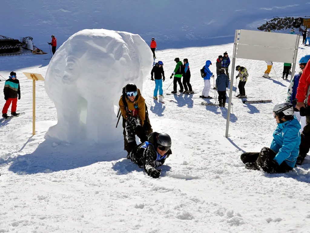 Jugendliche vor einer Schneeskulptur an der Bergstation.